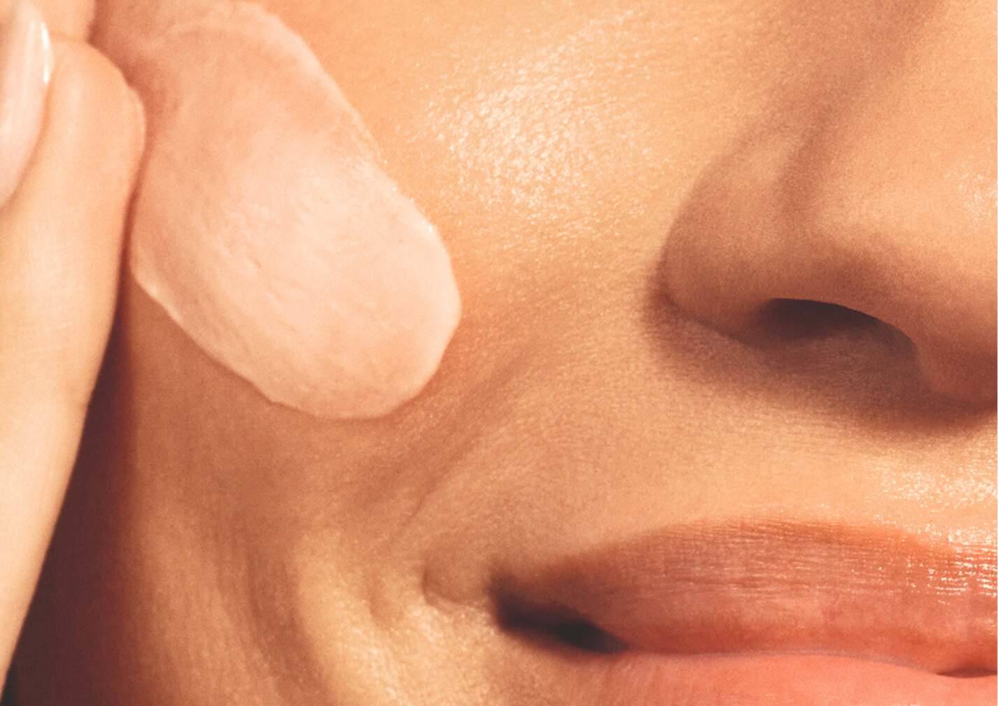 Femme qui étale de la crème sur son visage
